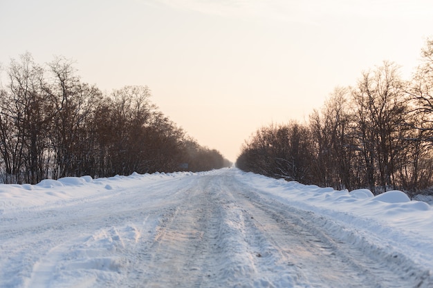Hiver route mal dégagée. Route à la campagne parsemée de neige. Paysage d'hiver avec des congères