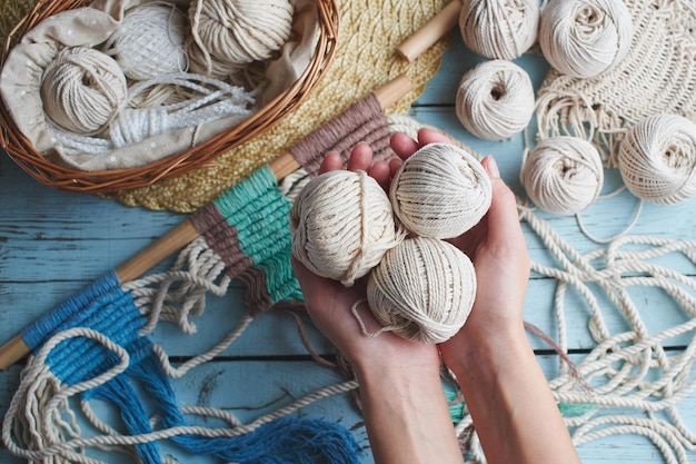 Hobby tricot macramé vue de dessus de la main et du fil sur une planche de bois