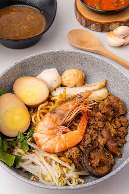 Hokkien mee sont jetés dans du saindoux de porc et servis avec des boulettes de poisson crevettes