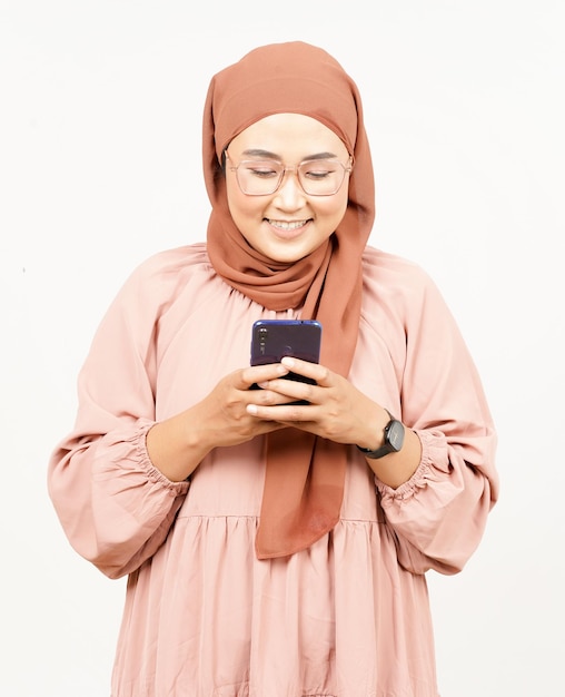 Holding Smartphone de belle femme asiatique portant le hijab isolé sur fond blanc