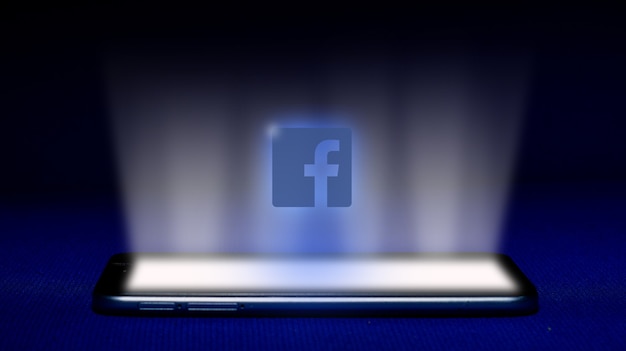 Photo hologramme du logo facebook. image du logo facebook hologramme sur fond bleu.