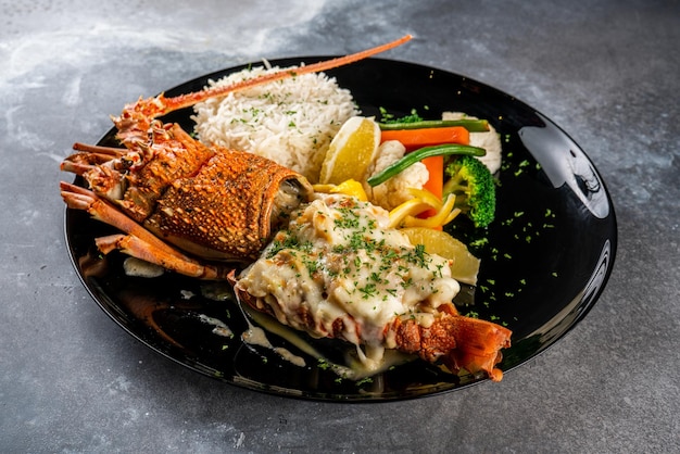 Homard Thermidor avec du riz servi dans un plat isolé sur fond sombre côté vue alimentaire