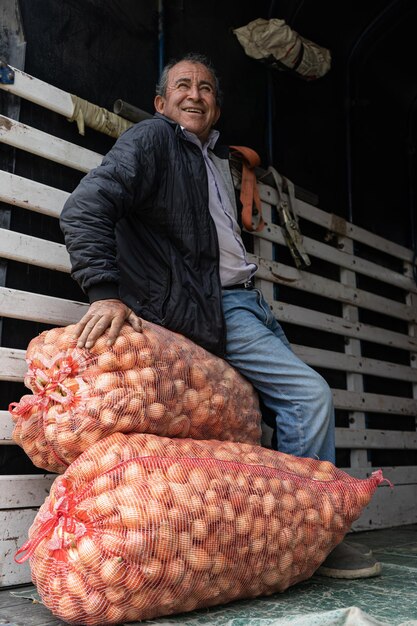 Photo hombre sentado en costales de cebolla sobre caminn homme assis sur des sacs d'oignons sur un camion