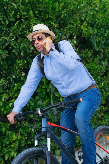 Un homme de 40 ans en tenue décontractée parle sur son téléphone portable en faisant du vélo.