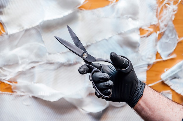 Homme de 62 ans coupant des fibres avec des ciseaux dans l'atelier.