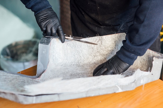 Homme de 62 ans coupant des fibres avec des ciseaux dans l'atelier.