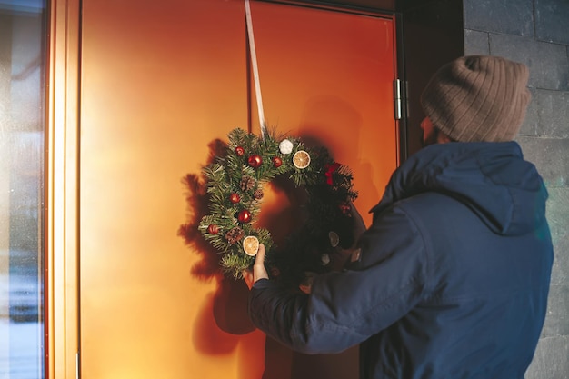 Homme accrochant la guirlande de Noël à la porte