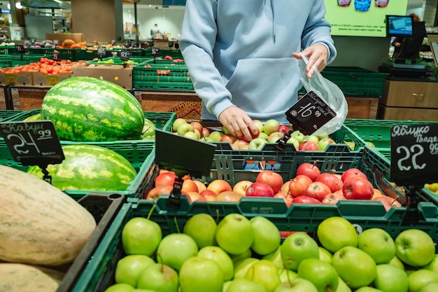 Un homme achète de la nourriture Un client masculin choisit des pommes en prenant des produits sur les étagères