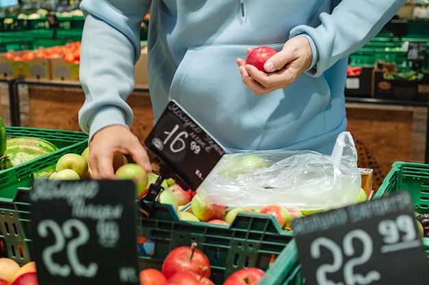 Un homme achète de la nourriture Un client masculin choisit des pommes en prenant des produits sur les étagères