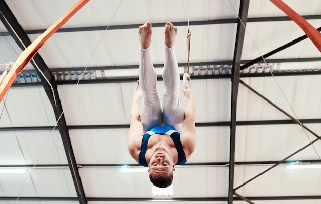 Homme acrobate et gymnastique à l'envers sur des anneaux en forme pour l'entraînement ou l'entraînement au gymnase