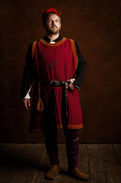 Homme acteur dans un costume médiéval du XVe siècle sur un fond stylisé vieilli Reconstitution de la vie médiévale
