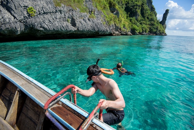 Un homme actif sur un bateau longtail traditionnel thaïlandais est prêt à faire de la plongée avec tuba et de la plongée, les îles Phi phi, Thaïlande