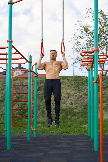 Homme actif s'entraînant en plein air sur des anneaux de gymnastique
