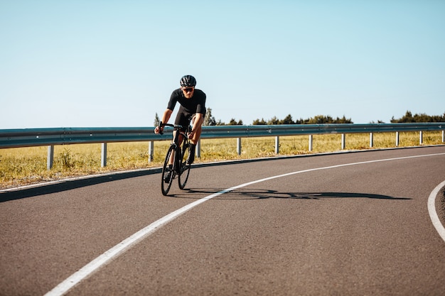 Homme actif en tenue de sport à vélo sur route pavée