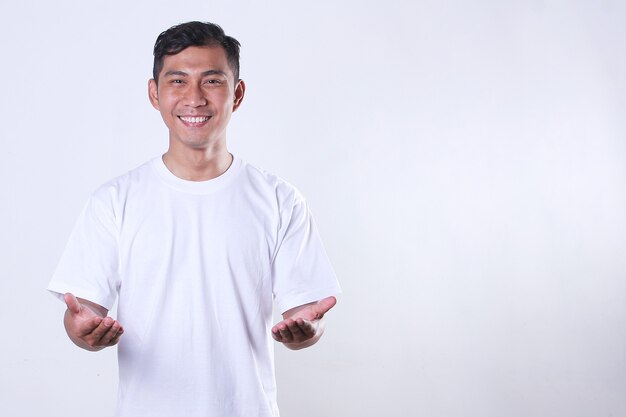 Un homme adulte asiatique portant un t-shirt blanc et montrant ses mains avec un visage souriant