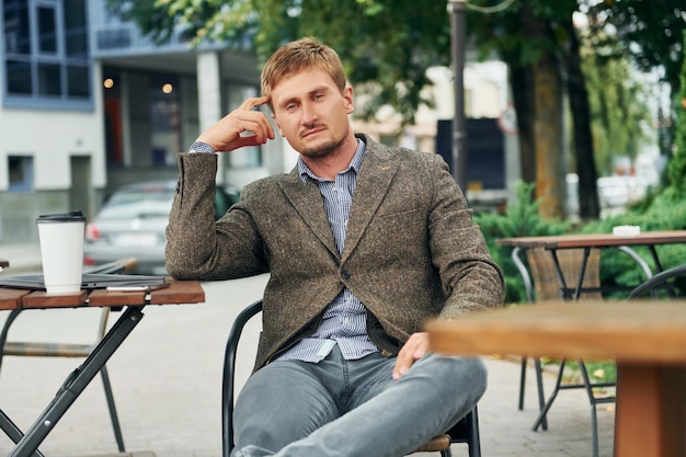 Homme adulte assis à l'extérieur à la table du café pendant la journée