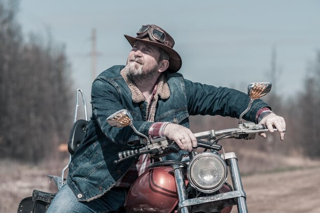 Photo homme adulte assis sur une moto dans la forêt