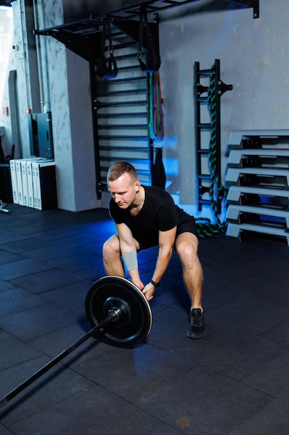 Homme adulte attirant faisant des exercices et soulevant des poids dans le gymnase. Entraînement sportif dans la salle de gym