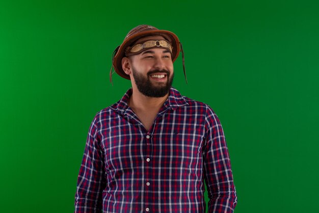 Homme adulte avec une barbe et portant une chemise à carreaux et un chapeau cangaceiro typique du festival brésilien de juin dans un studio tourné avec un fond vert