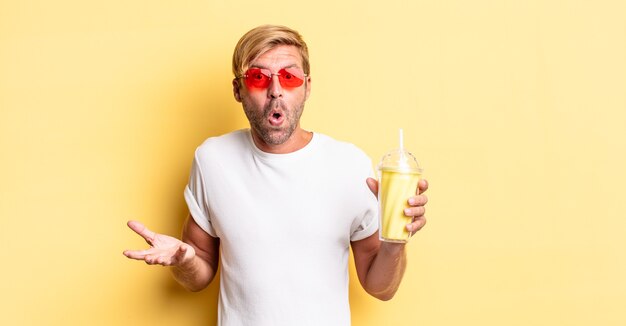 homme adulte blond étonné, choqué et étonné d'une incroyable surprise avec un milk-shake