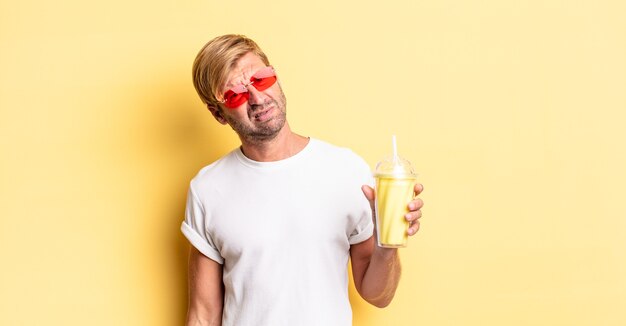 Homme adulte blond se sentant perplexe et confus avec un milk-shake