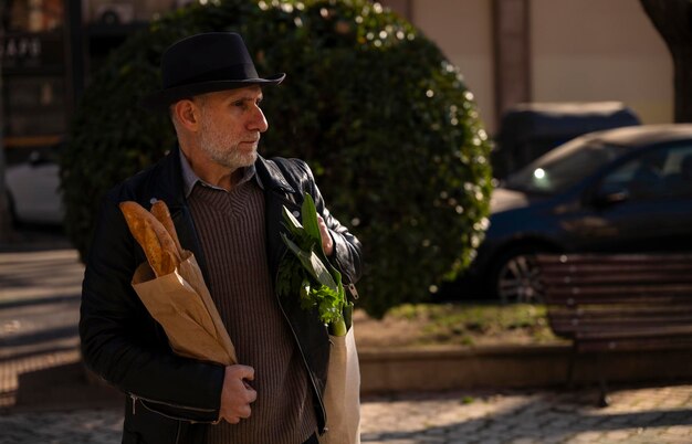 Homme adulte avec un chapeau tenant du pain et un sac de légumes dans la rue de Madrid, en Espagne