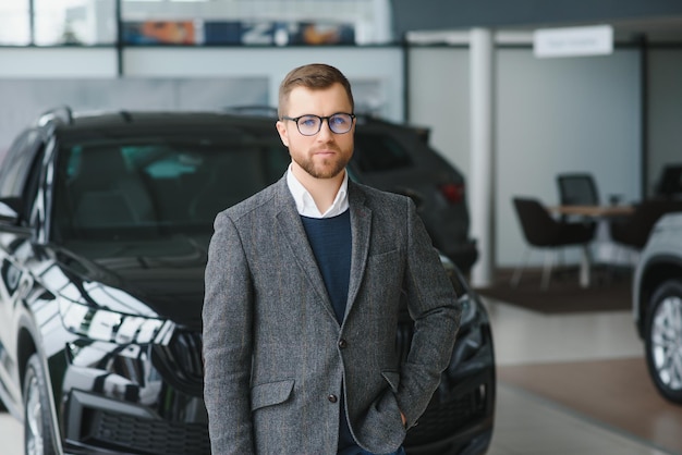 Homme adulte client acheteur masculin porte un costume classique chemise blanche choisit l'auto veut acheter une nouvelle voiture de contrôle tactile automobile dans la salle d'exposition salon de véhicule concessionnaire magasin salon de l'automobile concept de vente intérieur