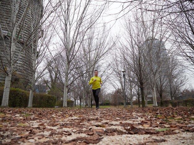 Homme adulte courant dans le parc en hiver avec fond de ville