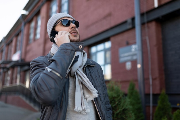 Homme adulte dans un chapeau et des lunettes de soleil parlant au téléphone à l'extérieur