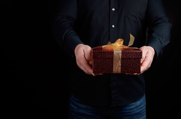 Homme adulte dans une chemise noire est titulaire d'une boîte carrée rouge avec un noeud noué