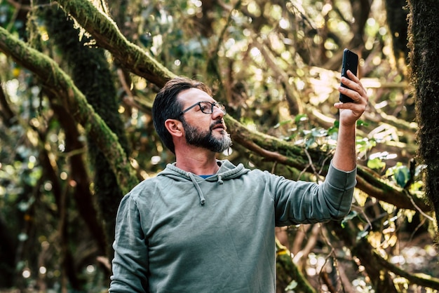 Homme adulte dans la forêt à la recherche d'un signal téléphonique internet