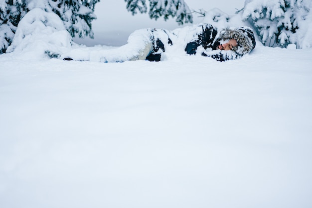 Homme adulte dormant sous les arbres enneigés