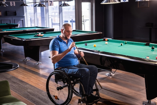 Homme adulte handicapé dans un fauteuil roulant jouer au billard dans le club