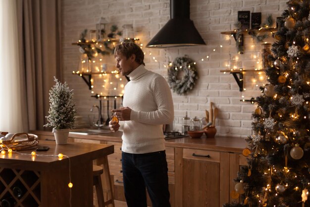 Un homme adulte à la maison dans la cuisine décorée de Noël