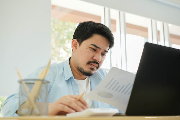 homme adulte moyen-oriental lisant un rapport de statistiques sur les bénéfices de l'entreprise avec émotion de stress