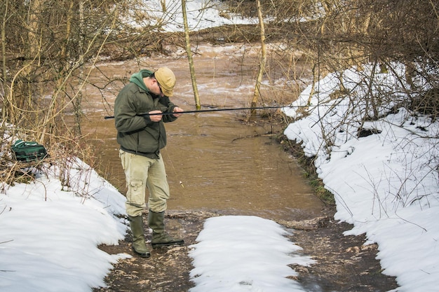 Un homme adulte pêche dans un lac en hiver.
