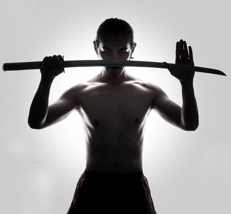 Photo homme adulte sans chemise tenant une épée alors qu'il se tient contre un fond blanc