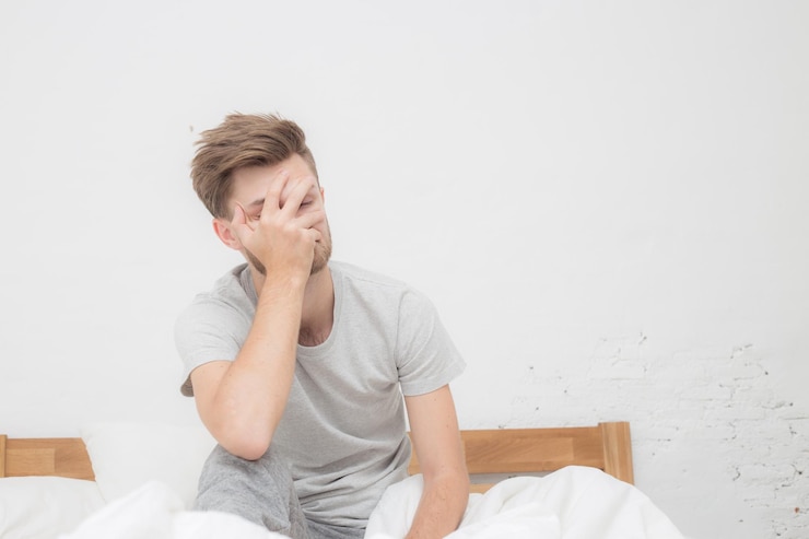 Photo un homme adulte stressé avec la tête à la main assis sur le lit à la maison