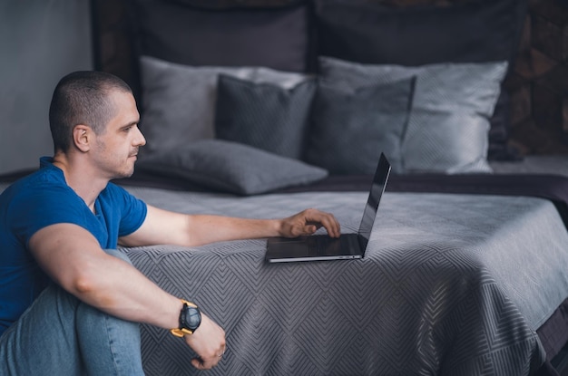 Photo homme adulte en t-shirt bleu travaillant sur ordinateur portable
