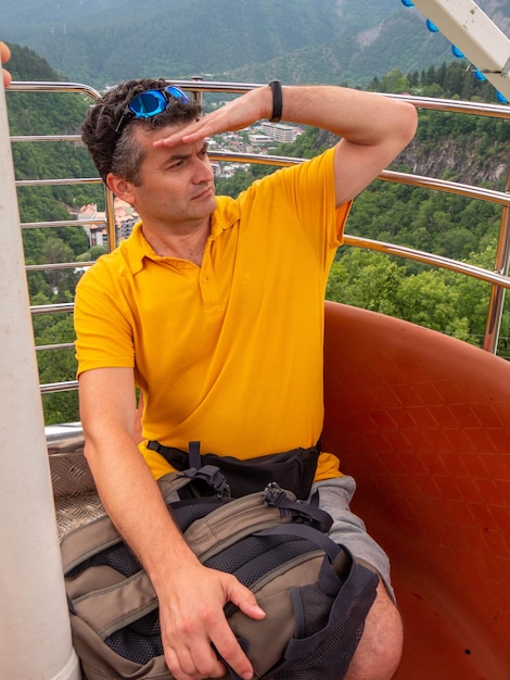 L'homme adulte sur le téléphérique regarde sur une montagne autour.