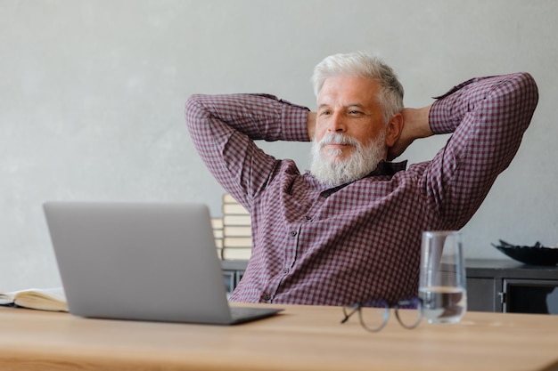 Homme d'affaires adulte aux cheveux gris travaille sur un ordinateur portable dans sa carrière de bureau finance et marketing