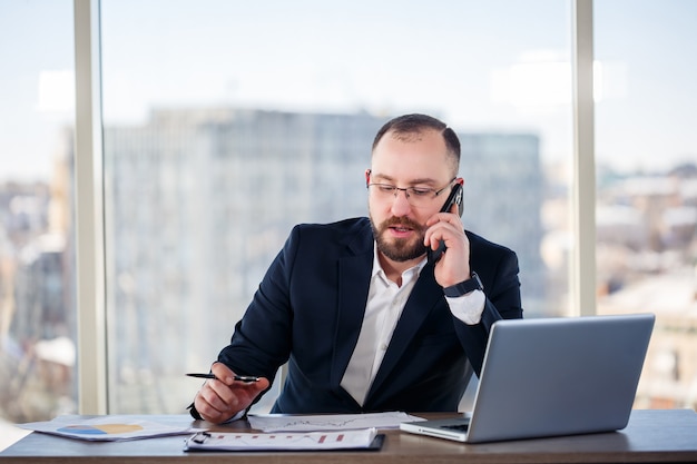 Homme d'affaires adulte, enseignant, mentor regarde un ordinateur portable dans son bureau. Bureau de travail. Développement d'un nouveau projet d'entreprise