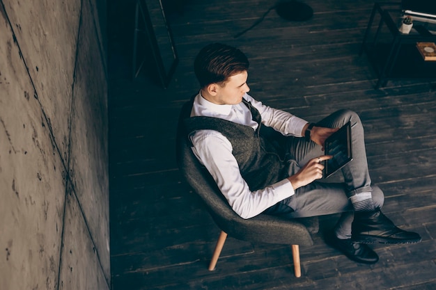 Homme D'affaires Adulte Masculin Assis Sur Une Chaise à Son Lieu De Travail, Vérifiant L'augmentation Des Ventes Sur Une Tablette.