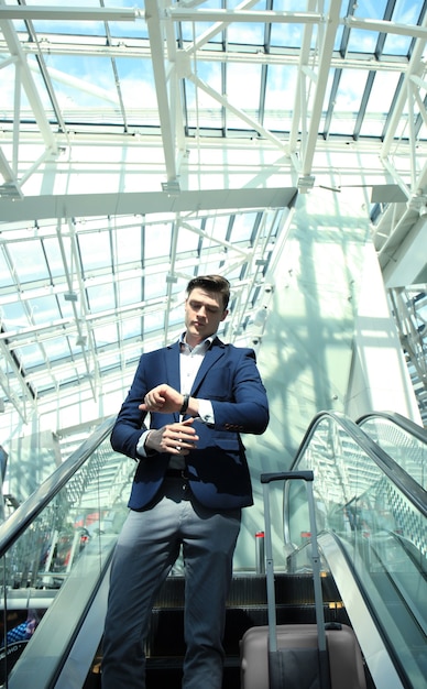 Homme d'affaires à l'aéroport en descendant l'escalator.