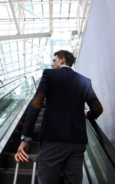 Homme d'affaires à l'aéroport en descendant l'escalator.