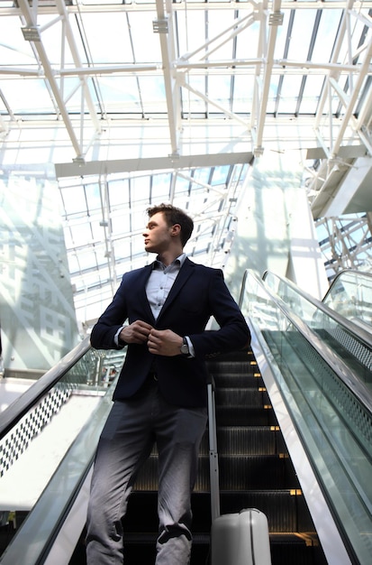 Homme d'affaires à l'aéroport en descendant l'escalator.