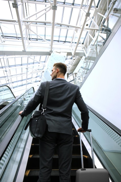 Homme d'affaires à l'aéroport en descendant l'escalator.