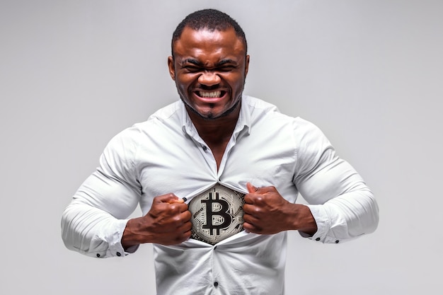 Homme d'affaires africain masculin fort déchire sa chemise. Bitcoin est visible sous la chemise