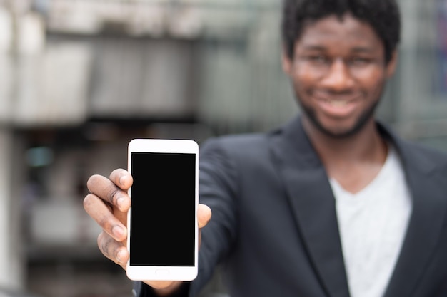 Homme d'affaires africain montrant un écran de smartphone vierge