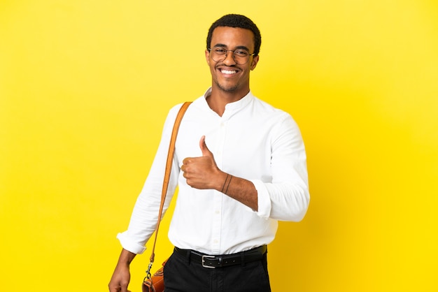 Homme d'affaires afro-américain sur fond jaune isolé donnant un geste du pouce vers le haut